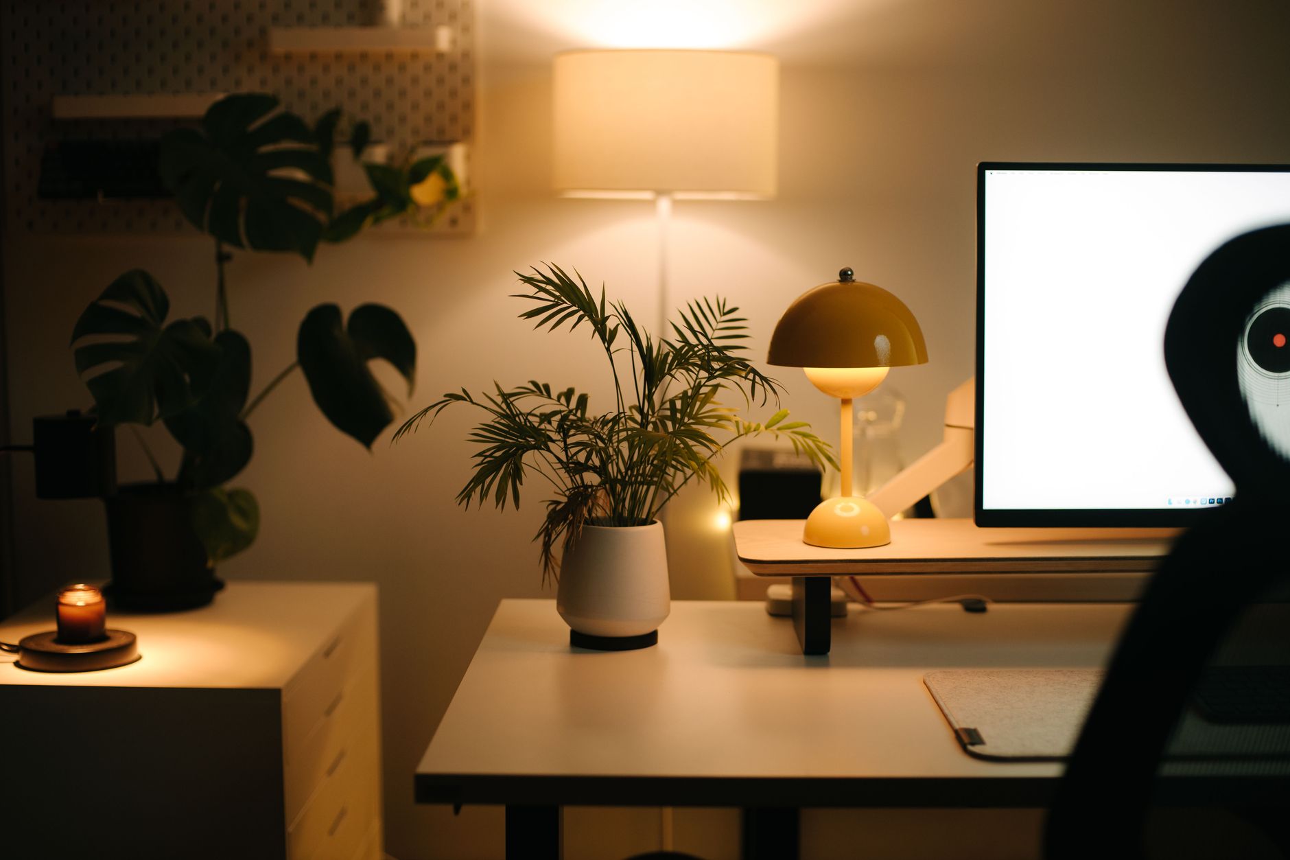Cálido escritorio de oficina en casa con iluminación ambiental y plantas, propio de quienes trabajan desde casa.