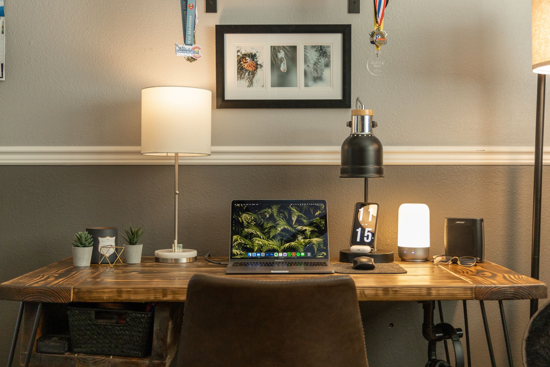 Escritorio de oficina en casa bien organizado con portátil, decoración e iluminación ambiental.